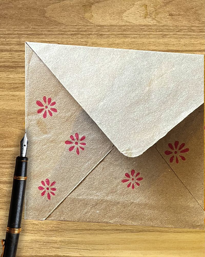 Envelope stamped with red flowers and a fountain pen