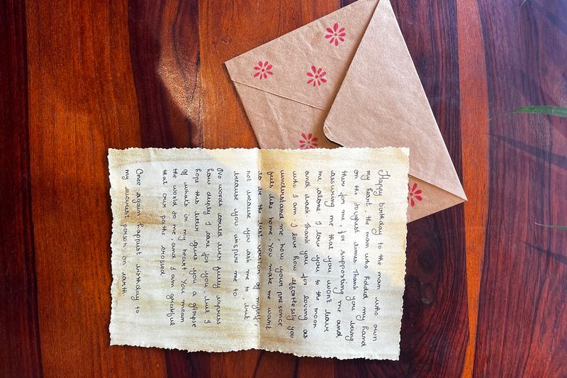 Handwritten birthday letter and envelope on a wooden table