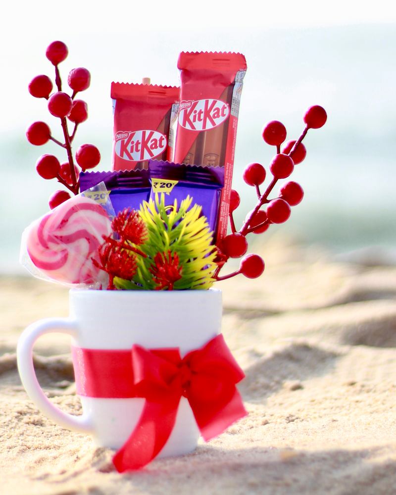 Christmas mini hamper in a white mug with chocolates, a lollipop and red berries